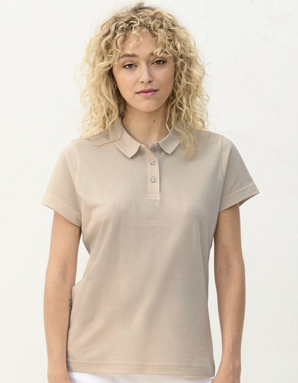 Vrouw met krullend blond haar draagt een beige polo en staat tegen een witte achtergrond.